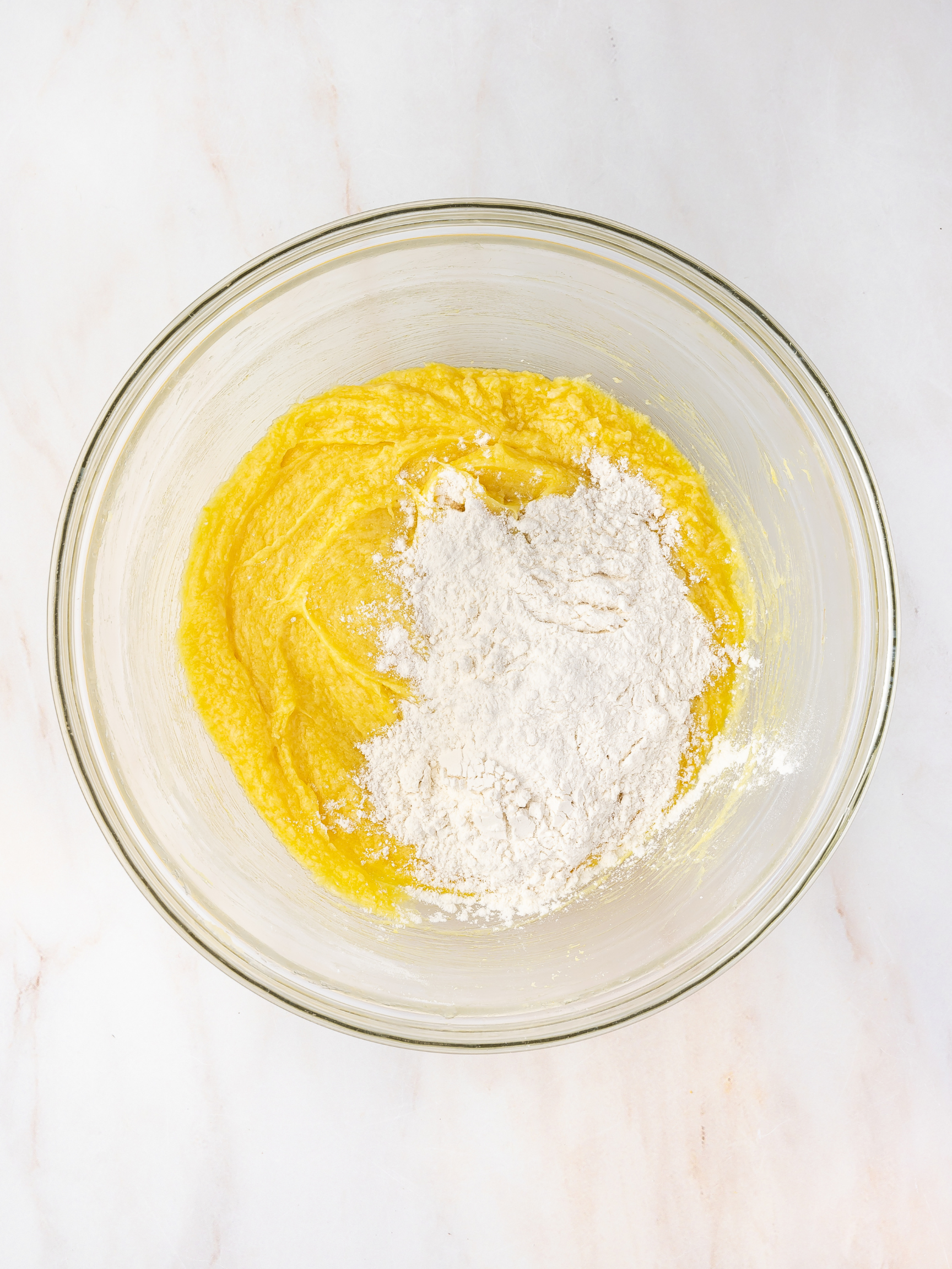 Flour mixture being gradually added to the wet ingredients in a mixing bowl to form cookie dough.