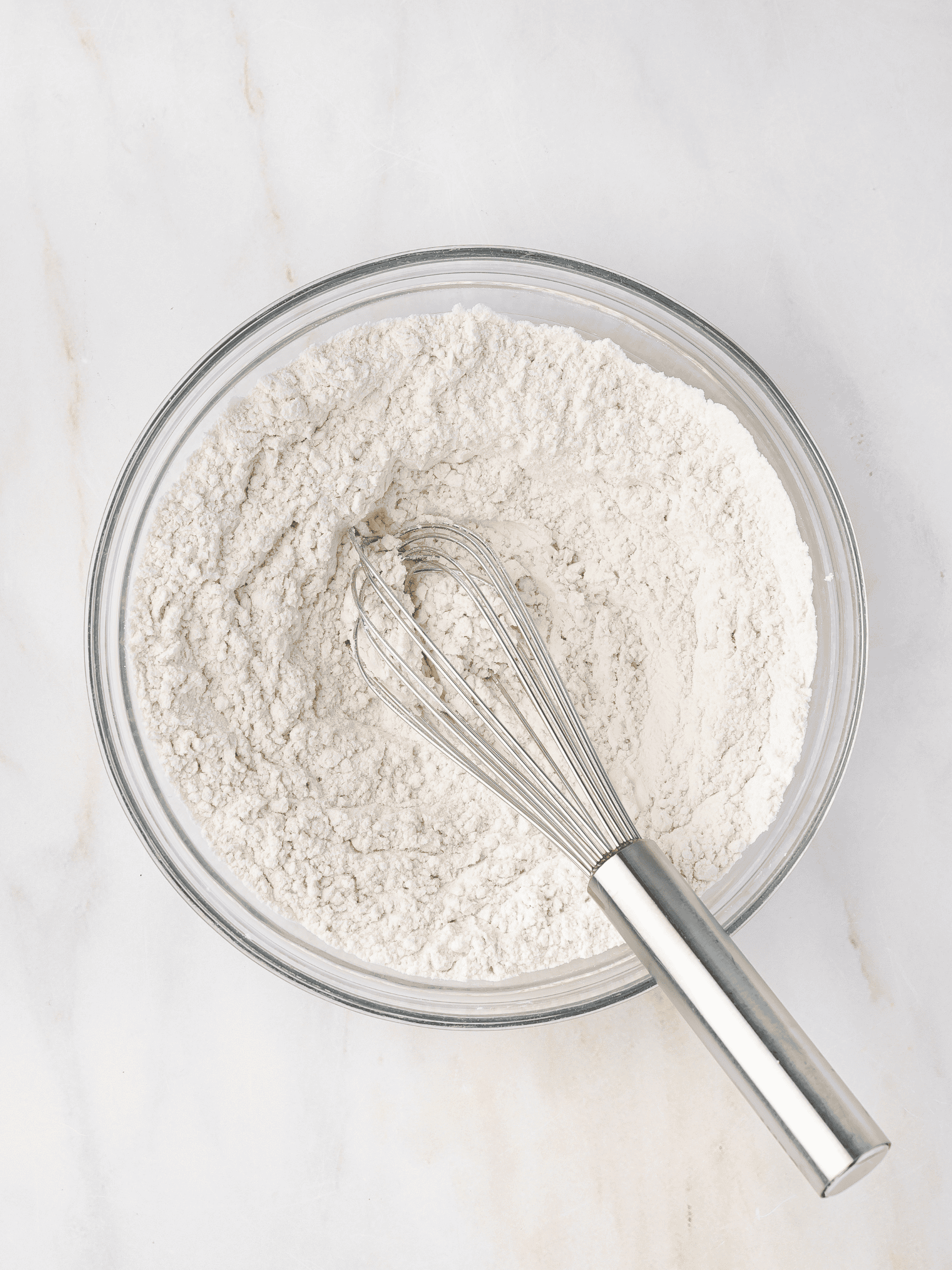 All-purpose flour, baking soda, and salt being whisked together in a mixing bowl for even distribution.