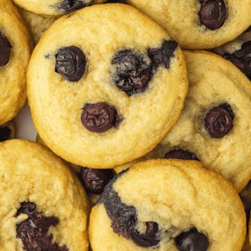 Lemon blueberry cookies arranged on a white ceramic platter, with fresh lemon slices and blueberries scattered around for garnish