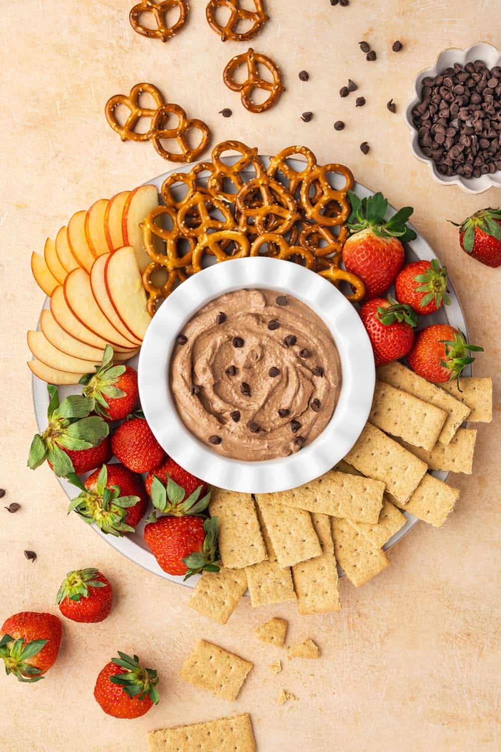 A bowl of creamy brownie batter dip surrounded by various dippers like strawberries, pretzels, apple slices, and graham crackers.