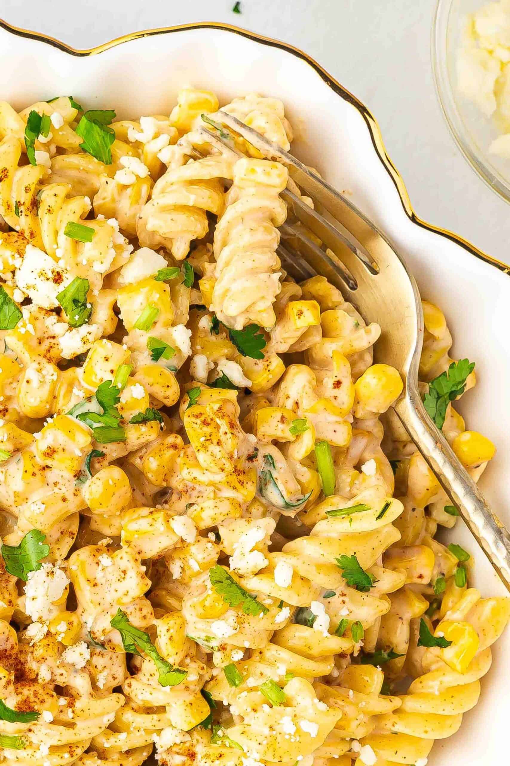 A creamy and flavorful Mexican street corn pasta salad in a white bowl, garnished with fresh cilantro and cotija cheese.