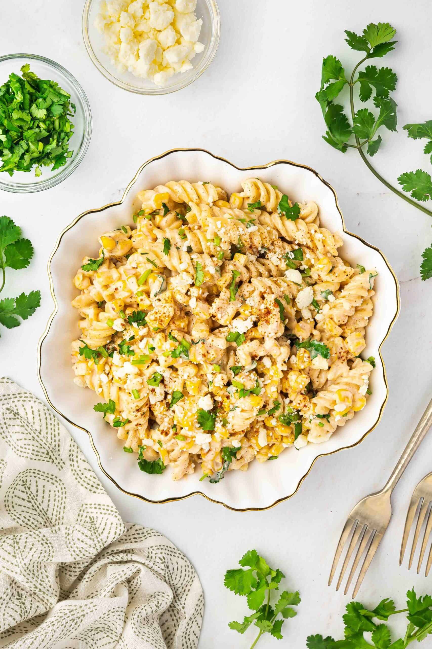 A serving of creamy street corn pasta salad on a white plate, ready to be enjoyed.