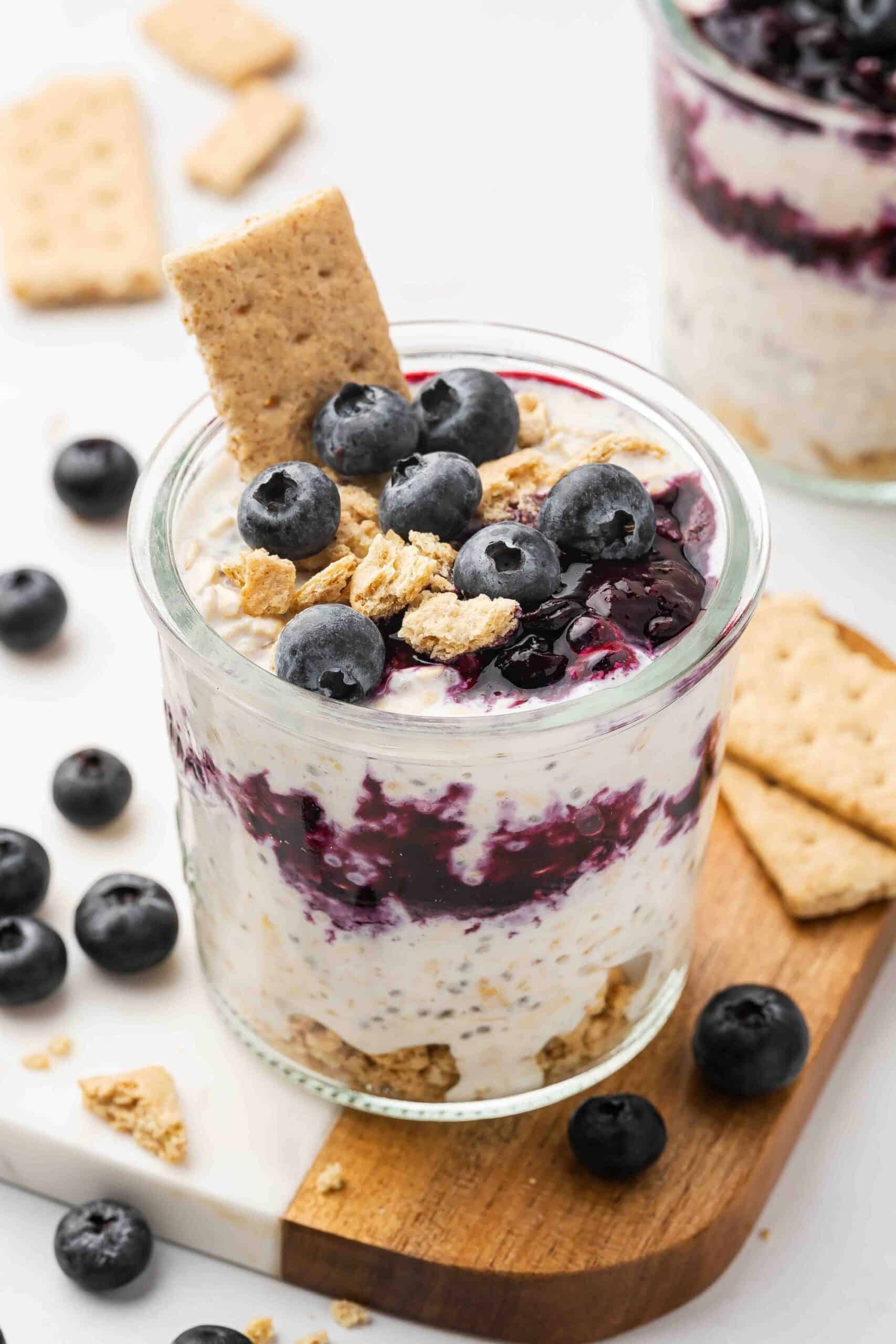 Blueberry Cheesecake Overnight Oats in a glass cup with blueberries on top