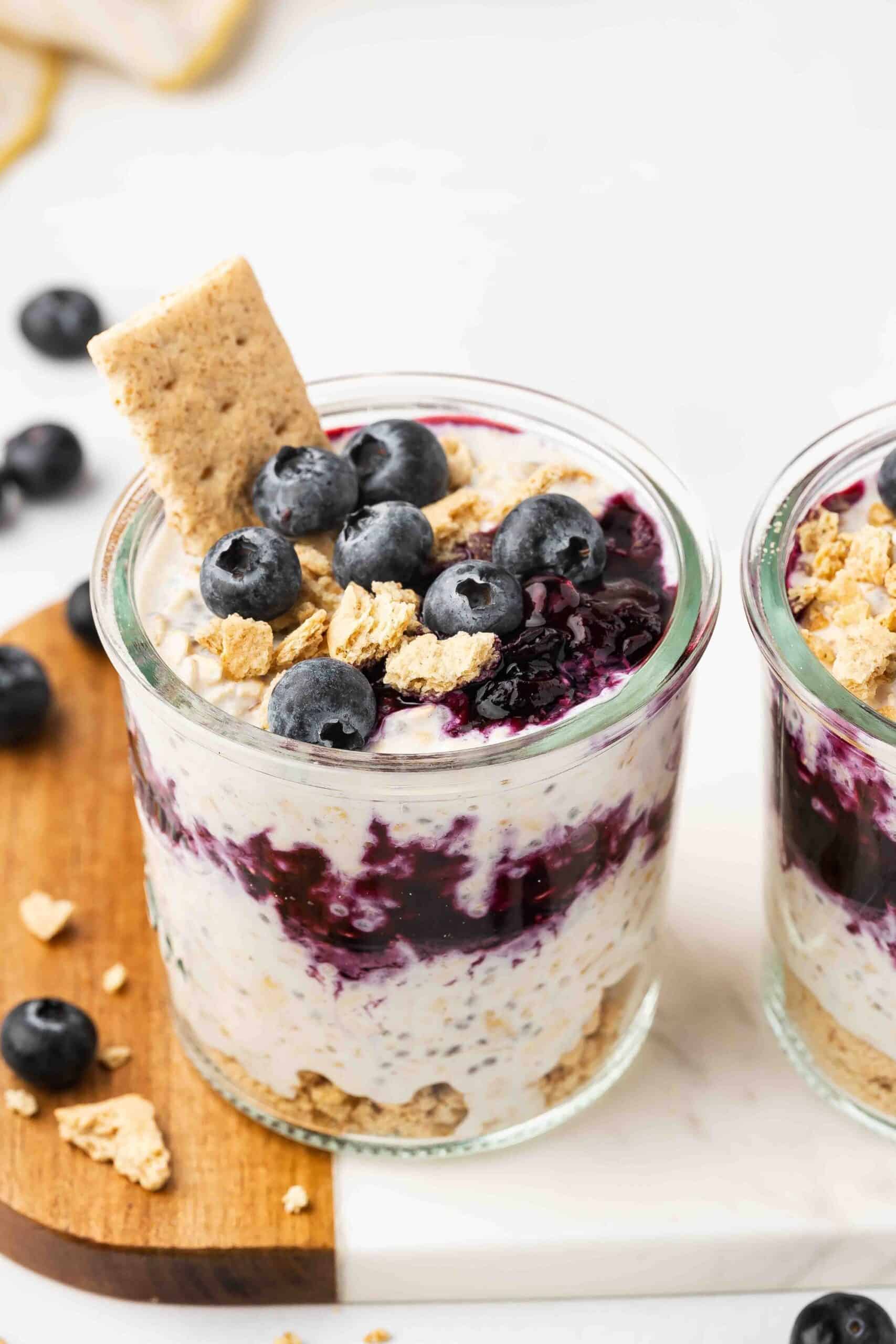 Blueberry Cheesecake Overnight Oats in a glass cup with blueberries on top