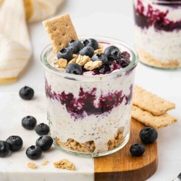 Blueberry Cheesecake Overnight Oats in a glass cup with blueberries on top