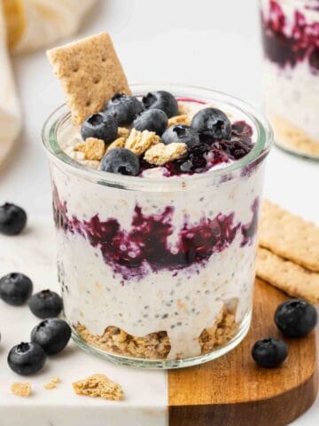 Blueberry Cheesecake Overnight Oats in a glass cup with blueberries on top