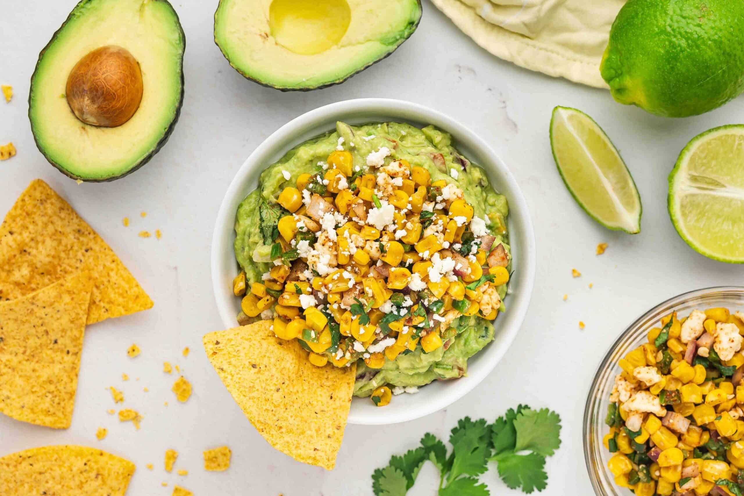 Overhead shot of Mexican street corn guacamole with a handful of tortilla chips around it.