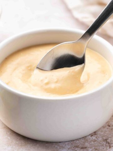 Spicy garlic aioli in a small dish with a spoon, perfect for dipping shrimp.