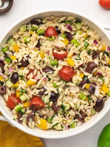 Close-up of Mediterranean orzo pasta salad with cucumbers, cherry tomatoes, and olives.