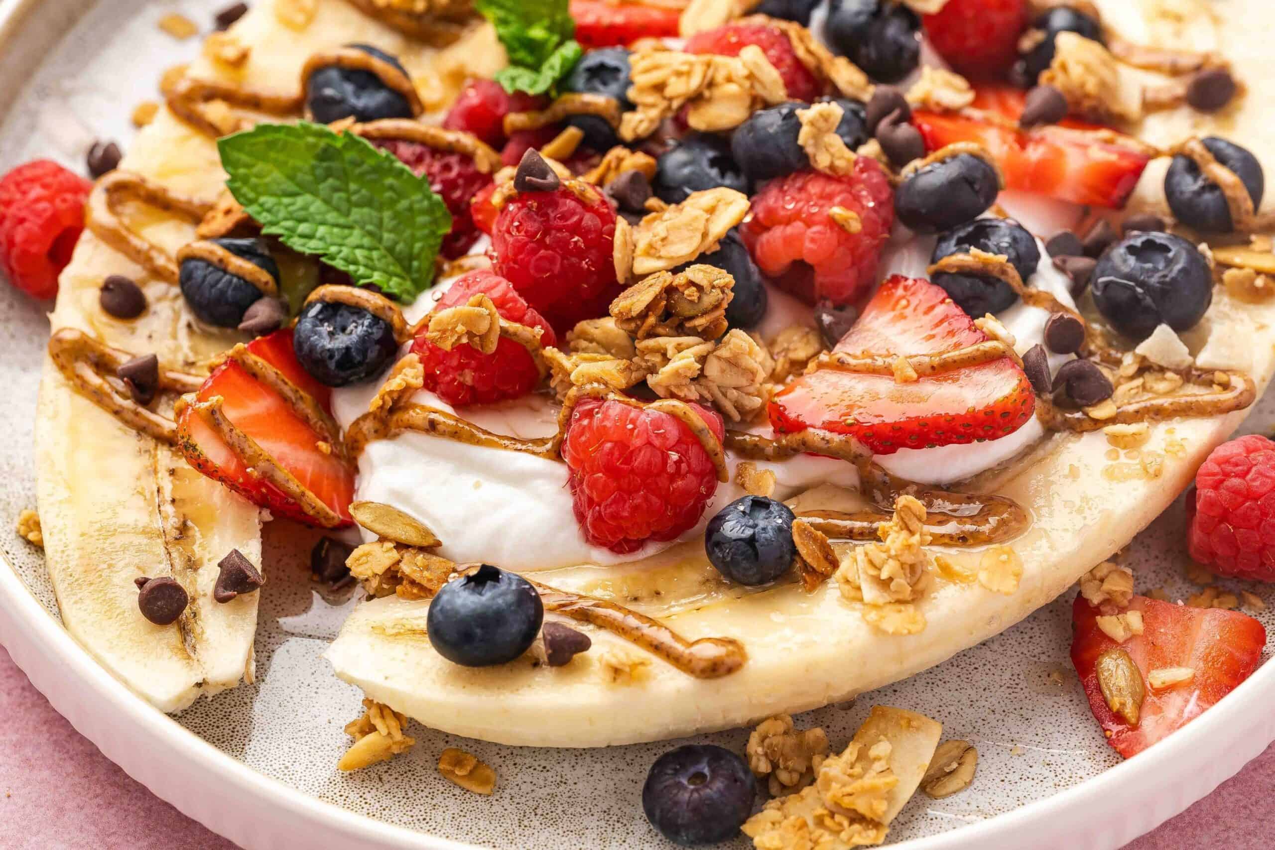 Close-up of a yogurt banana split with crunchy granola, chia seeds, and a swirl of almond butter.