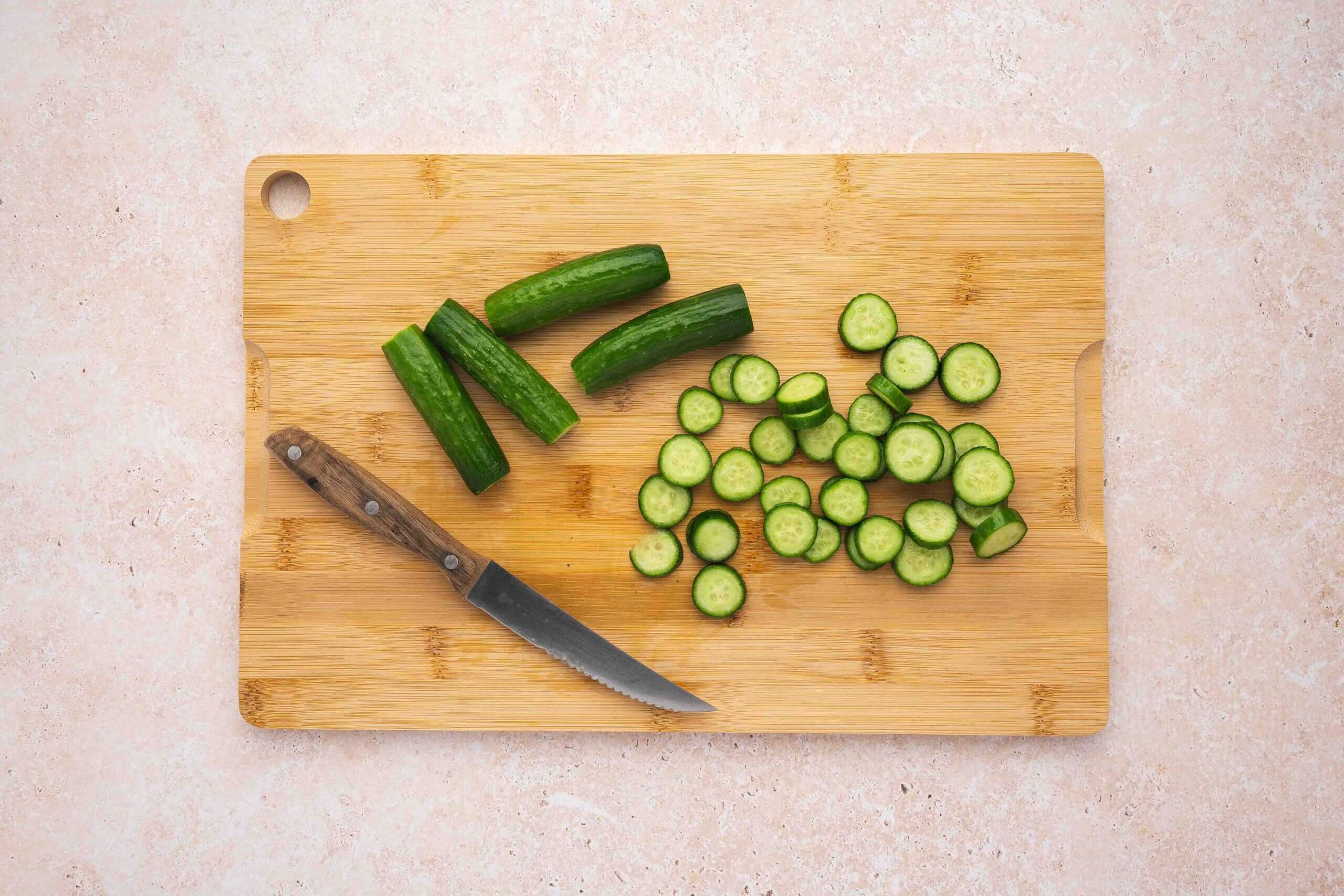 Thinly sliced cucumbers and sweet mini peppers arranged on a cutting board