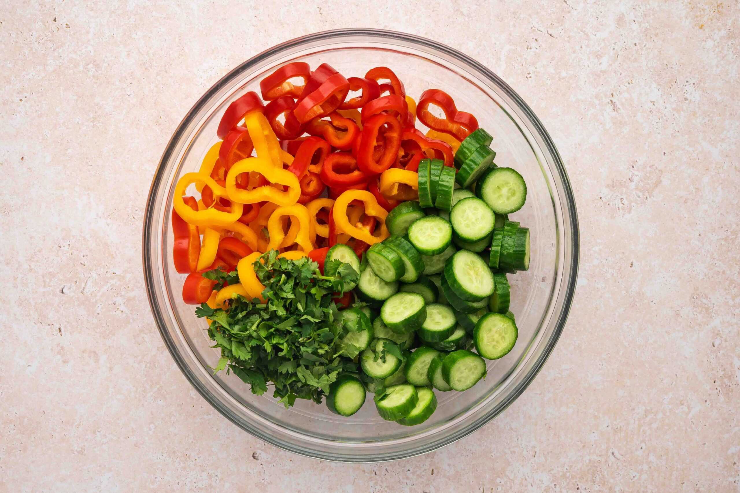 Bowl of sliced cucumbers, sweet peppers, and chopped cilantro