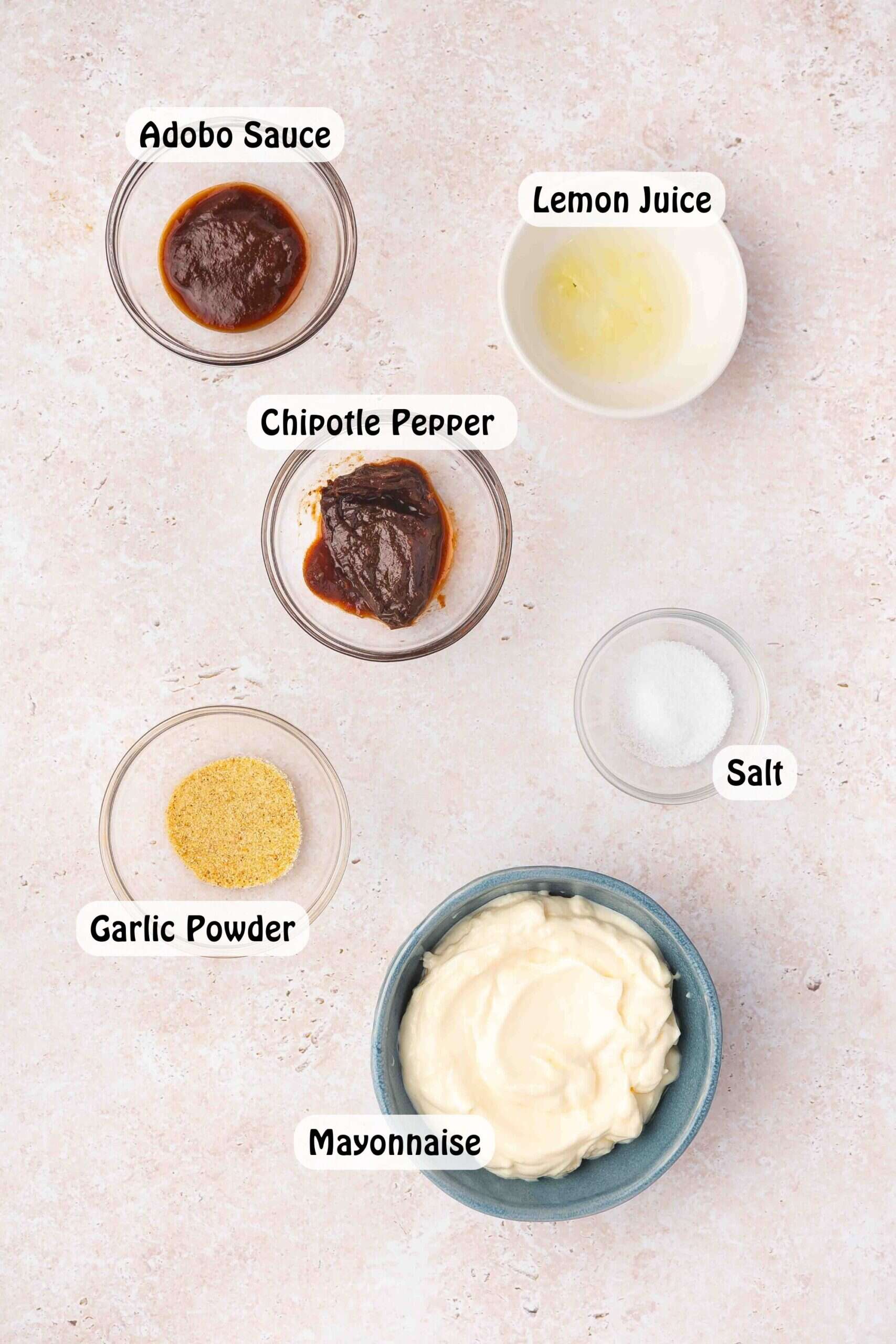 Ingredients for homemade chipotle sauce including mayonnaise, chipotle pepper, adobo sauce, lime juice, and salt neatly arranged on a kitchen counter