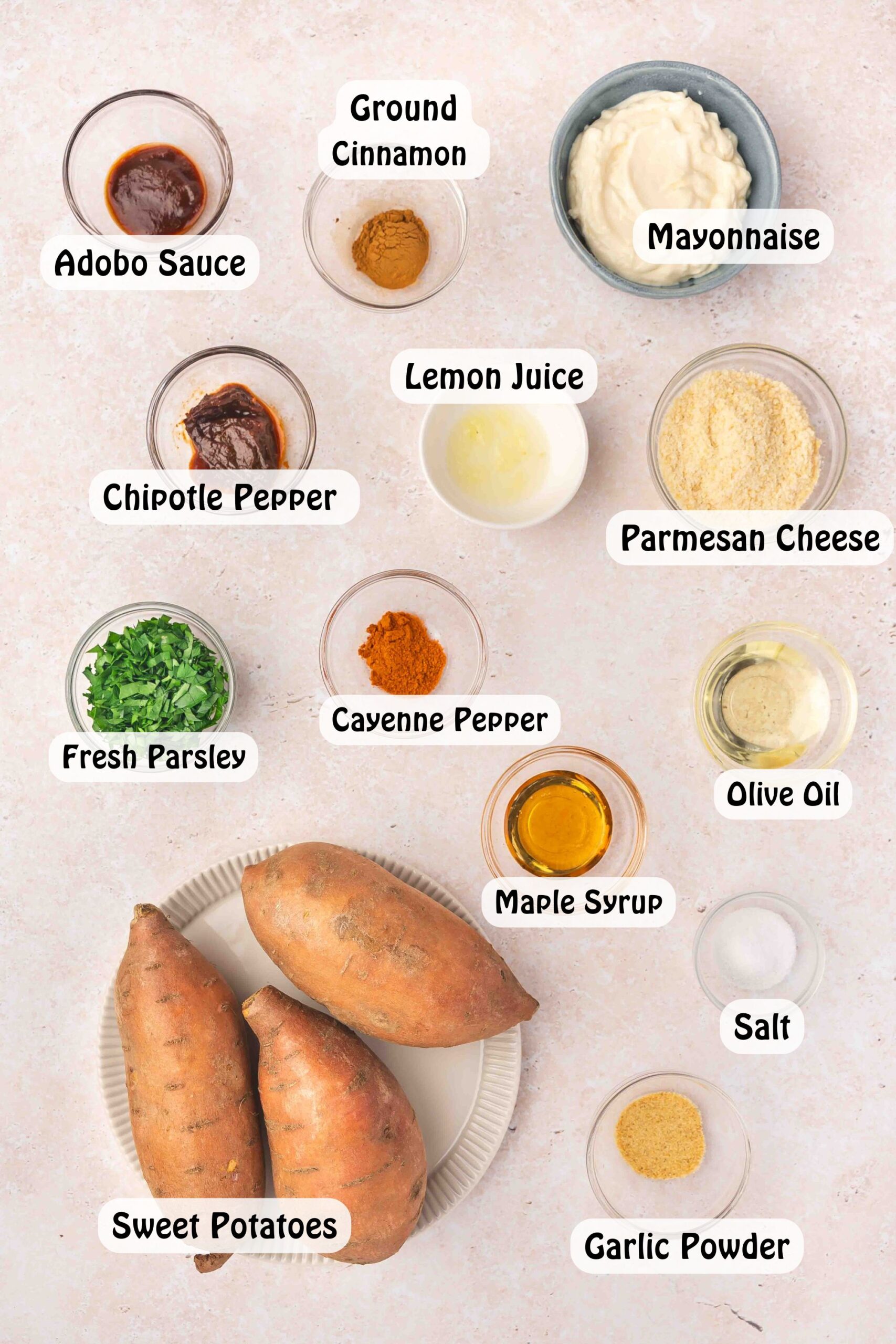Flat lay of raw sweet potato wedges, olive oil, spices, maple syrup, Parmesan, and parsley arranged neatly on a kitchen counter