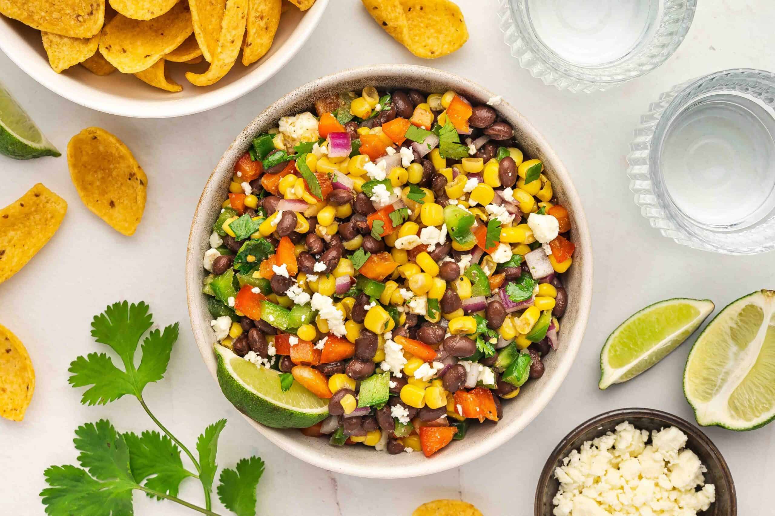 Corn dip setup for party with ceramic bowl and scattered Fritos