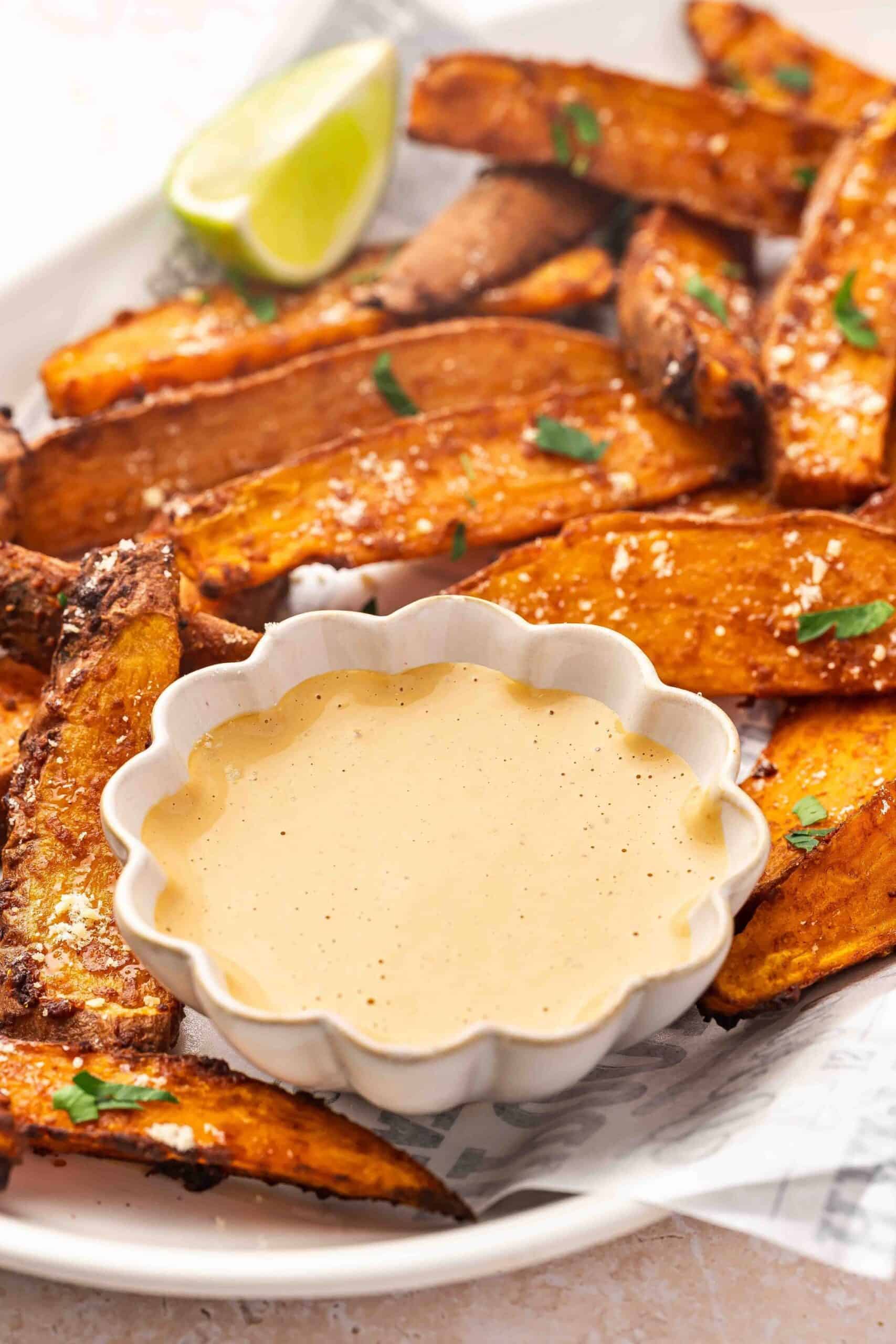 Close-up of crispy sweet potato wedges and smooth chipotle sauce