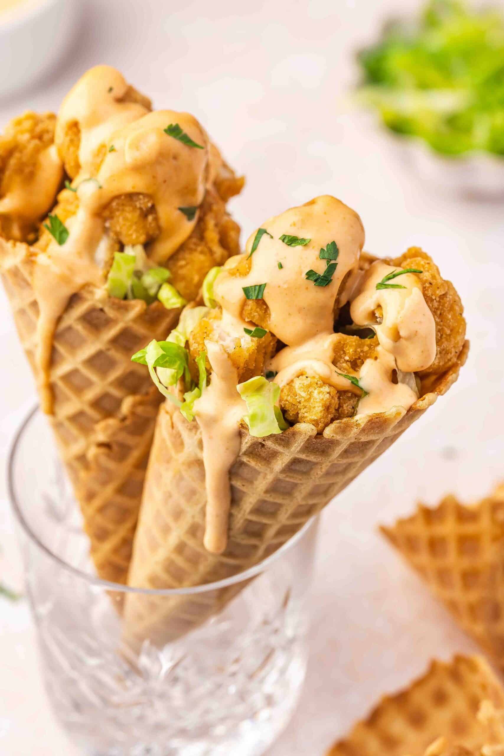 Chicken-stuffed waffle cone with vibrant toppings and creamy hot sauce
