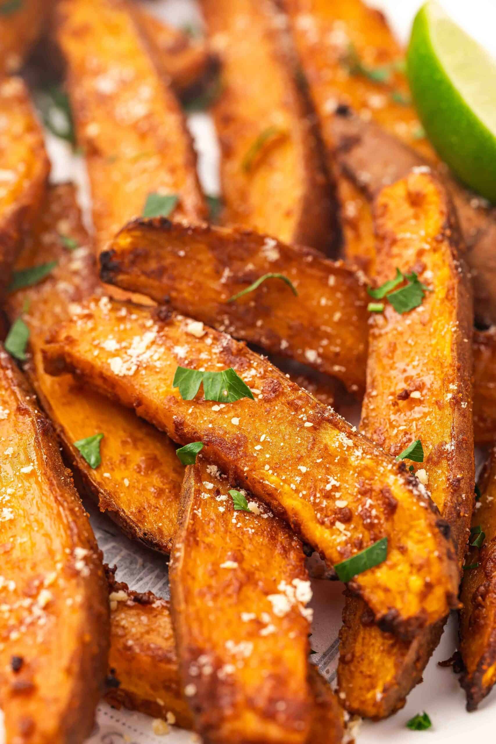 Close-up of golden crispy air fryer sweet potato wedge next to chipotle sauce