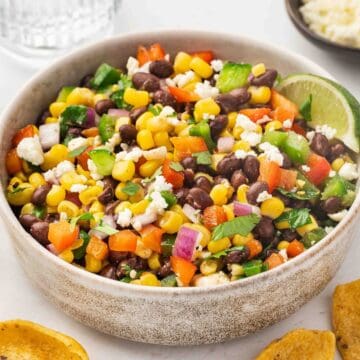 Black bean and corn dip in a ceramic bowl topped with feta