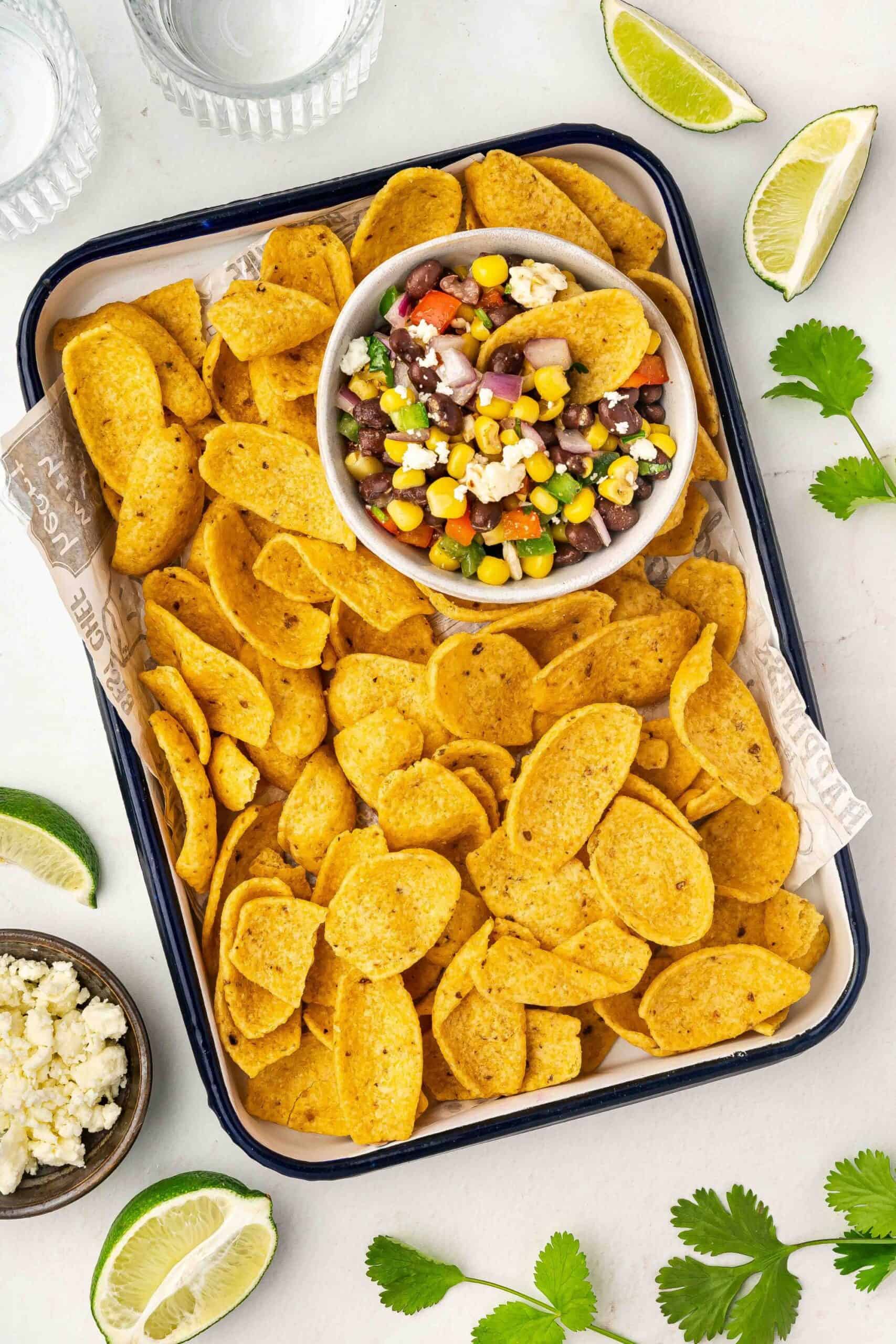 Snack board with black bean corn dip, chips, and herbs