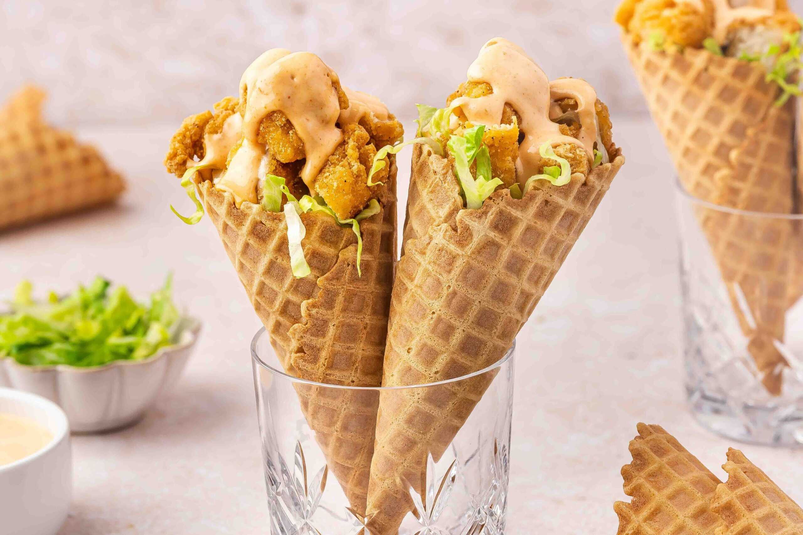 Crispy chicken nuggets layered in waffle cones with lettuce and spicy sauce