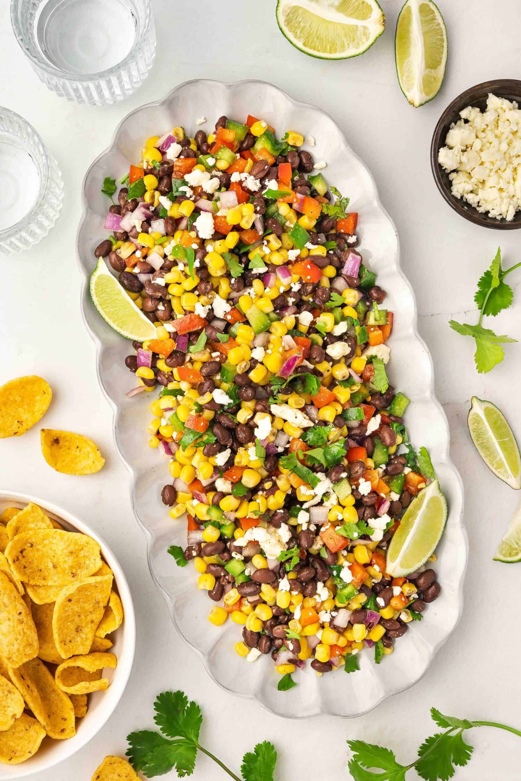 Black bean corn dip with lime and chips arranged for serving