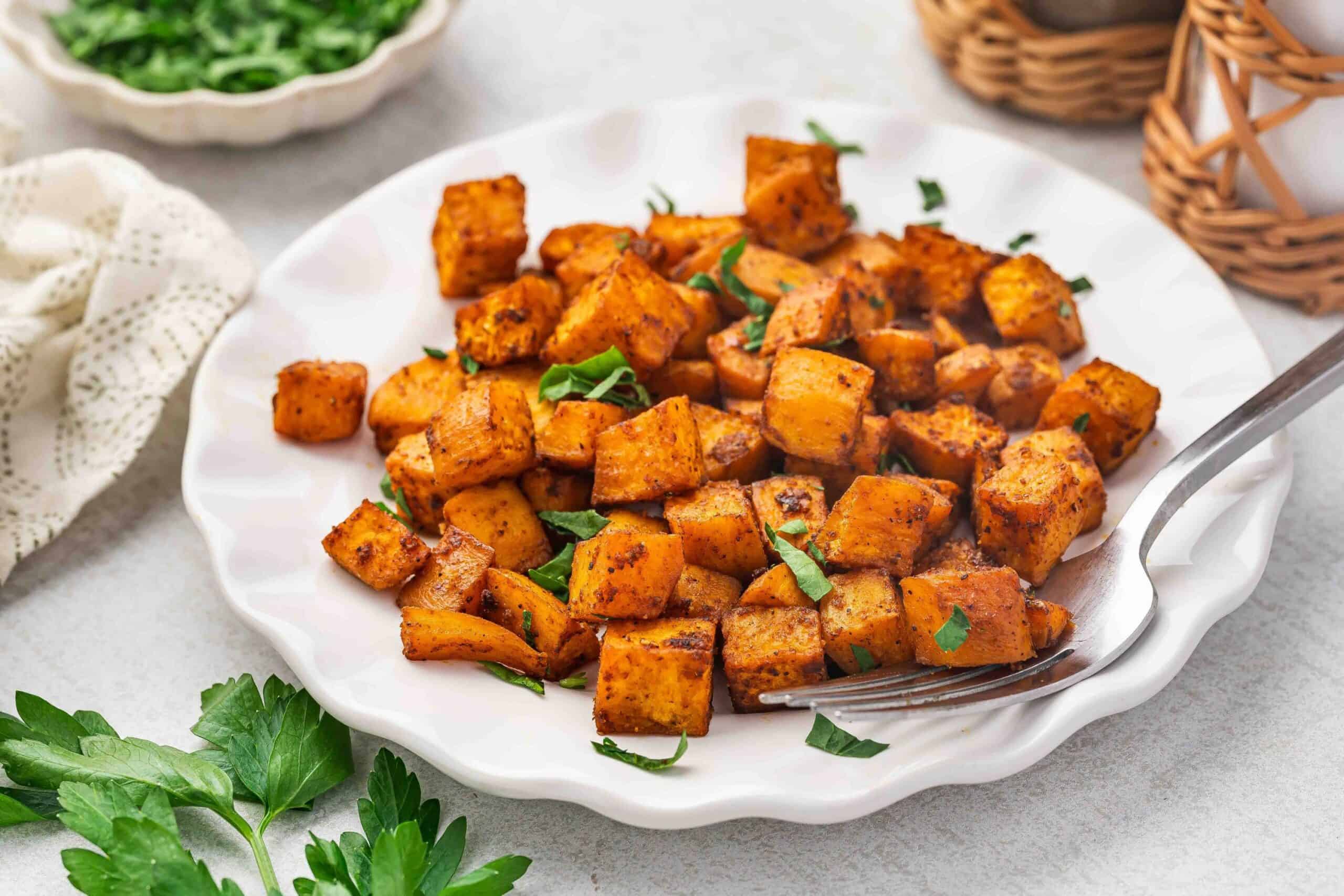 Close-up of crispy edges on roasted sweet potatoes on a serving plate.