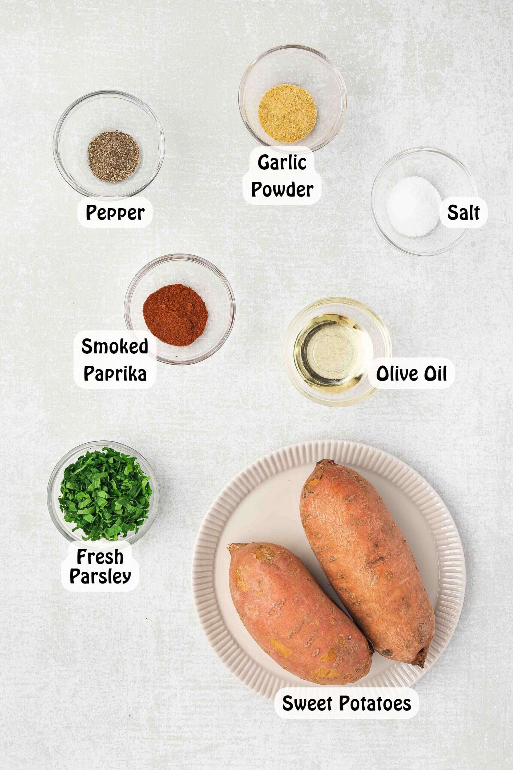 Ingredients for crispy roasted sweet potatoes: peeled sweet potatoes, olive oil, smoked paprika, garlic powder, salt, pepper, and fresh parsley.