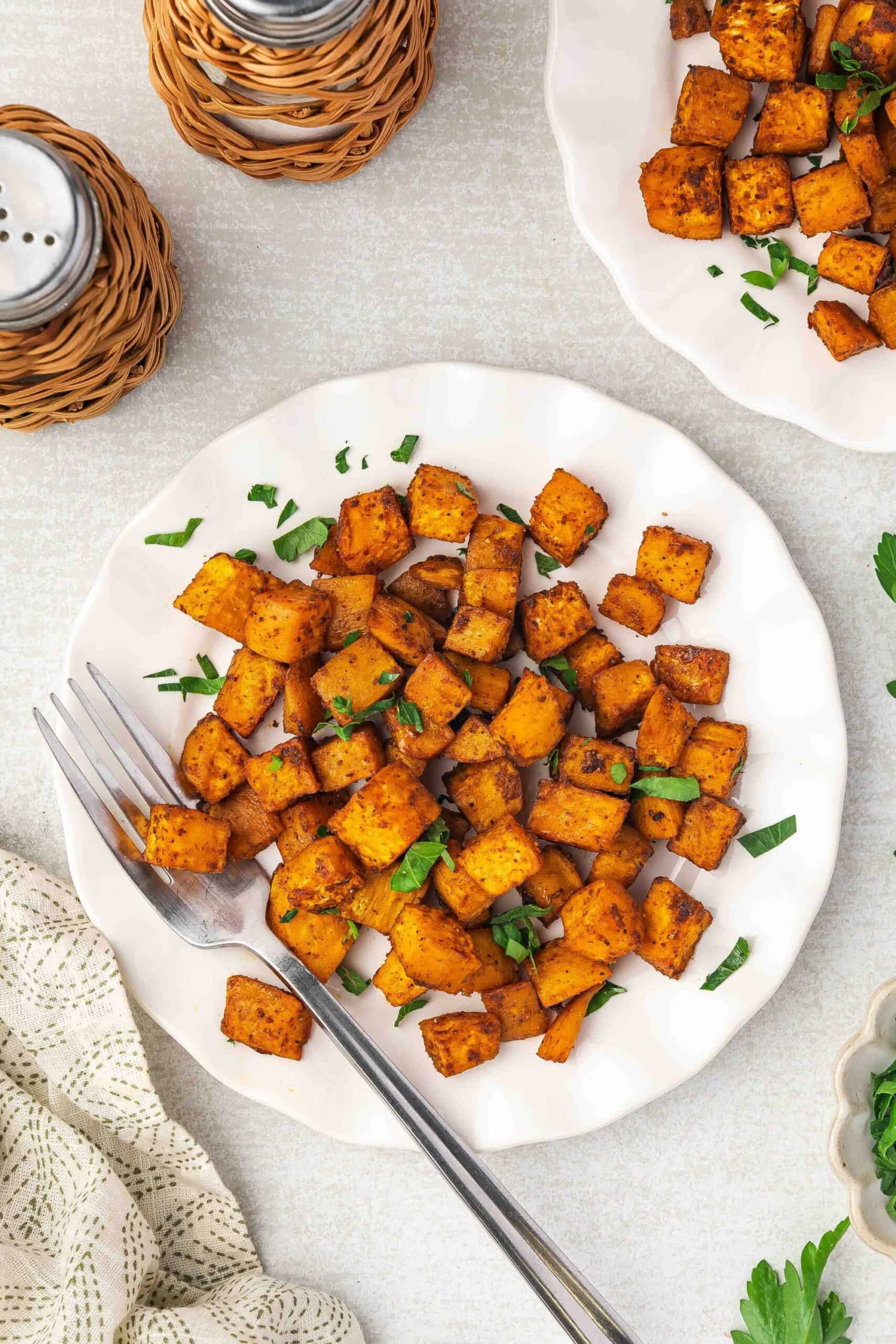 Macro shot showing texture of crispy roasted sweet potato cubes on a plate.