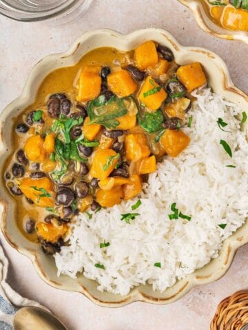 Sweet potato black bean coconut curry served with fluffy white rice in a bowl.