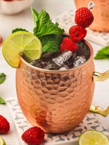 Refreshing Raspberry Moscow Mule cocktail in copper mug with fresh mint and raspberries.