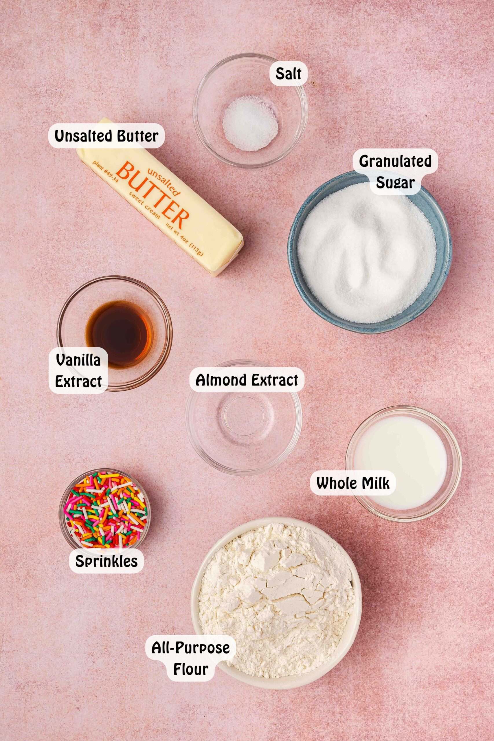Ingredients for edible sugar cookie dough: heat-treated flour, butter, sugar, milk, vanilla, almond extract, salt, and colorful sprinkles in bowls ready to mix.