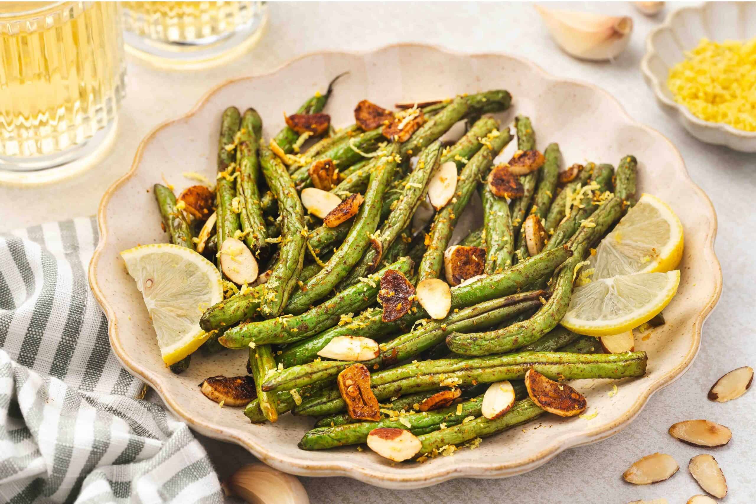 Oven-roasted green beans with garlic, lemon zest, and toasted almonds on a parchment-lined tray.