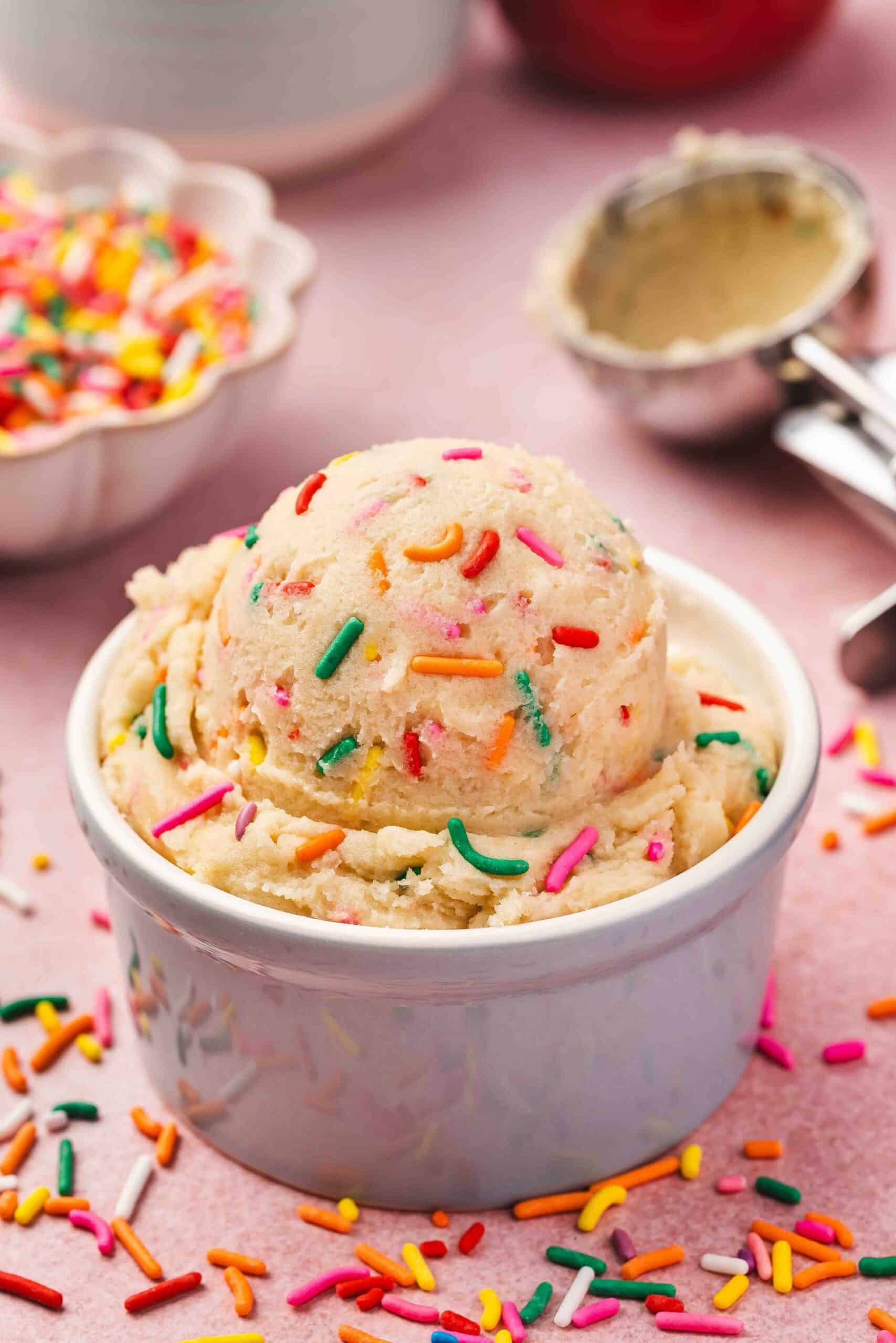 Homemade edible sugar cookie dough in a ceramic bowl, with spoon ready for scooping.
