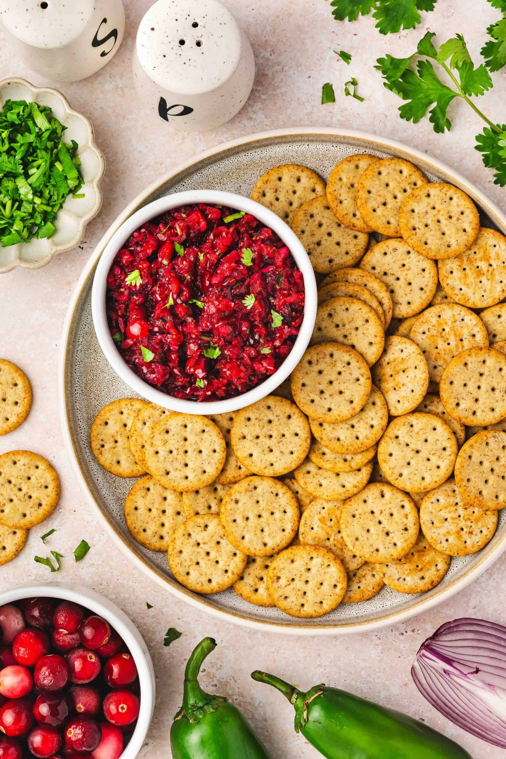 Cranberry jalapeño salsa served with multigrain crackers on a clean surface
