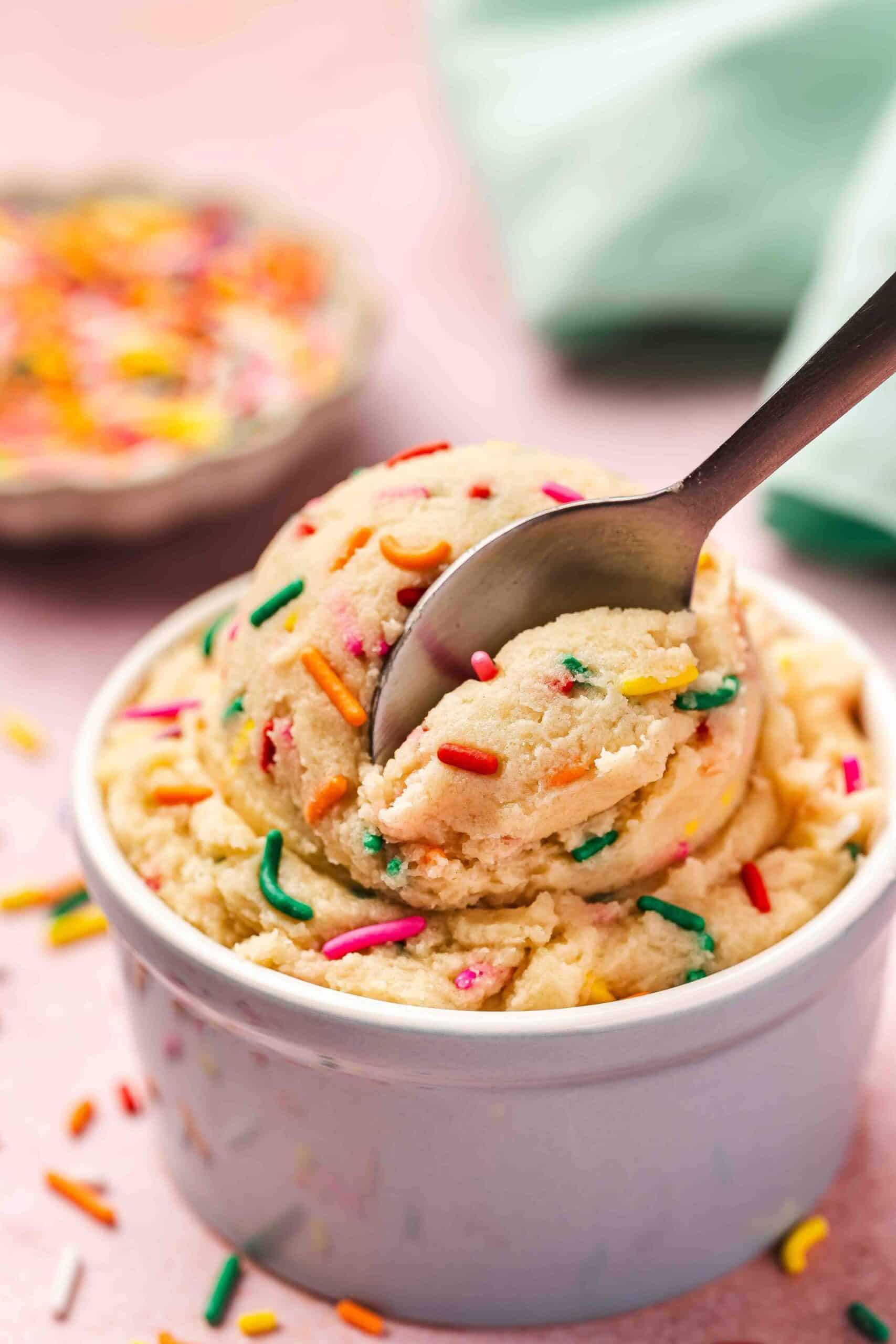 Close-up of soft, ready-to-eat sugar cookie dough in a smooth ceramic bowl.