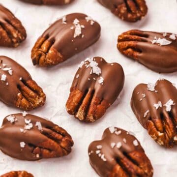 Close-up of glossy chocolate pecans on parchment paper ready to set.