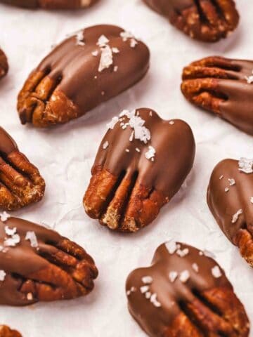 Close-up of glossy chocolate pecans on parchment paper ready to set.