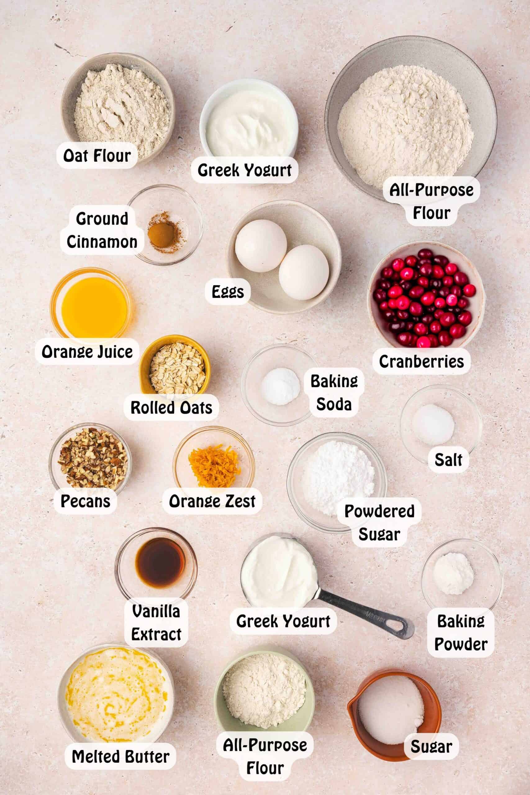 Ingredients for cranberry orange coffee cake arranged on a table including flour, oats, cranberries, orange, yogurt, butter, eggs, and sugar