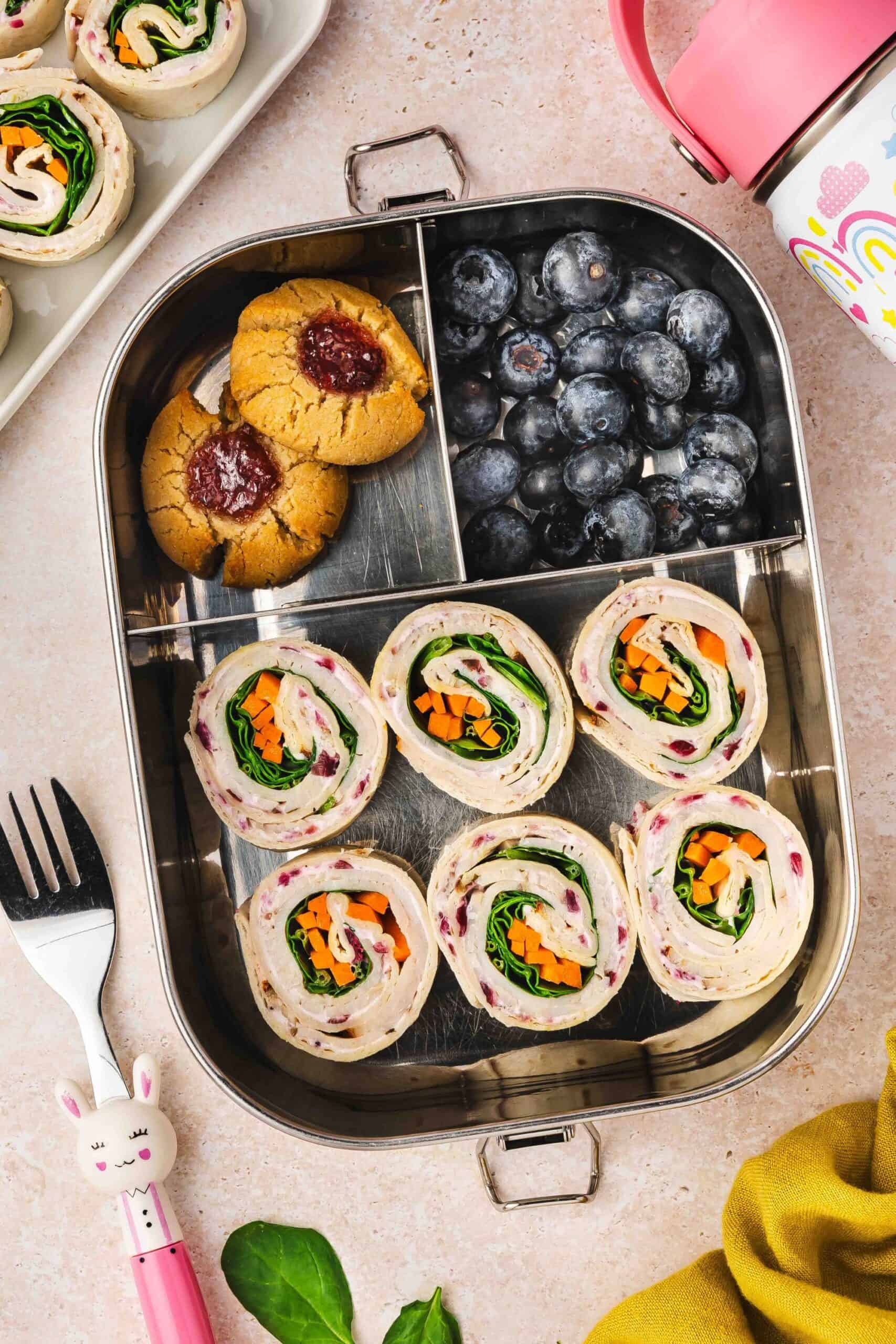 Easy make-ahead turkey roll-ups with cranberry cream cheese and fresh veggies packed for school or work lunch.