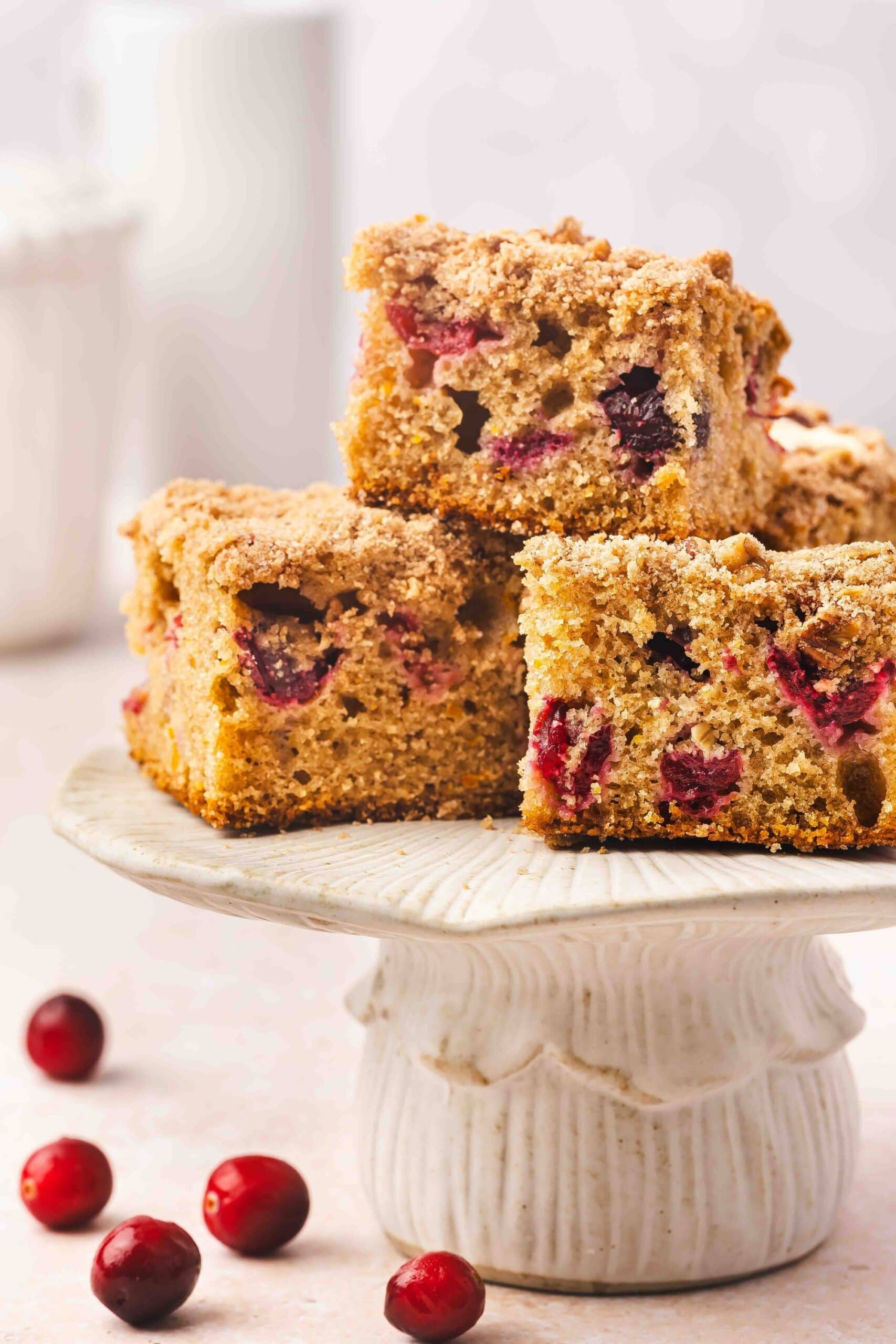 Cranberry orange coffee cake cut into squares with glaze drizzled on top
