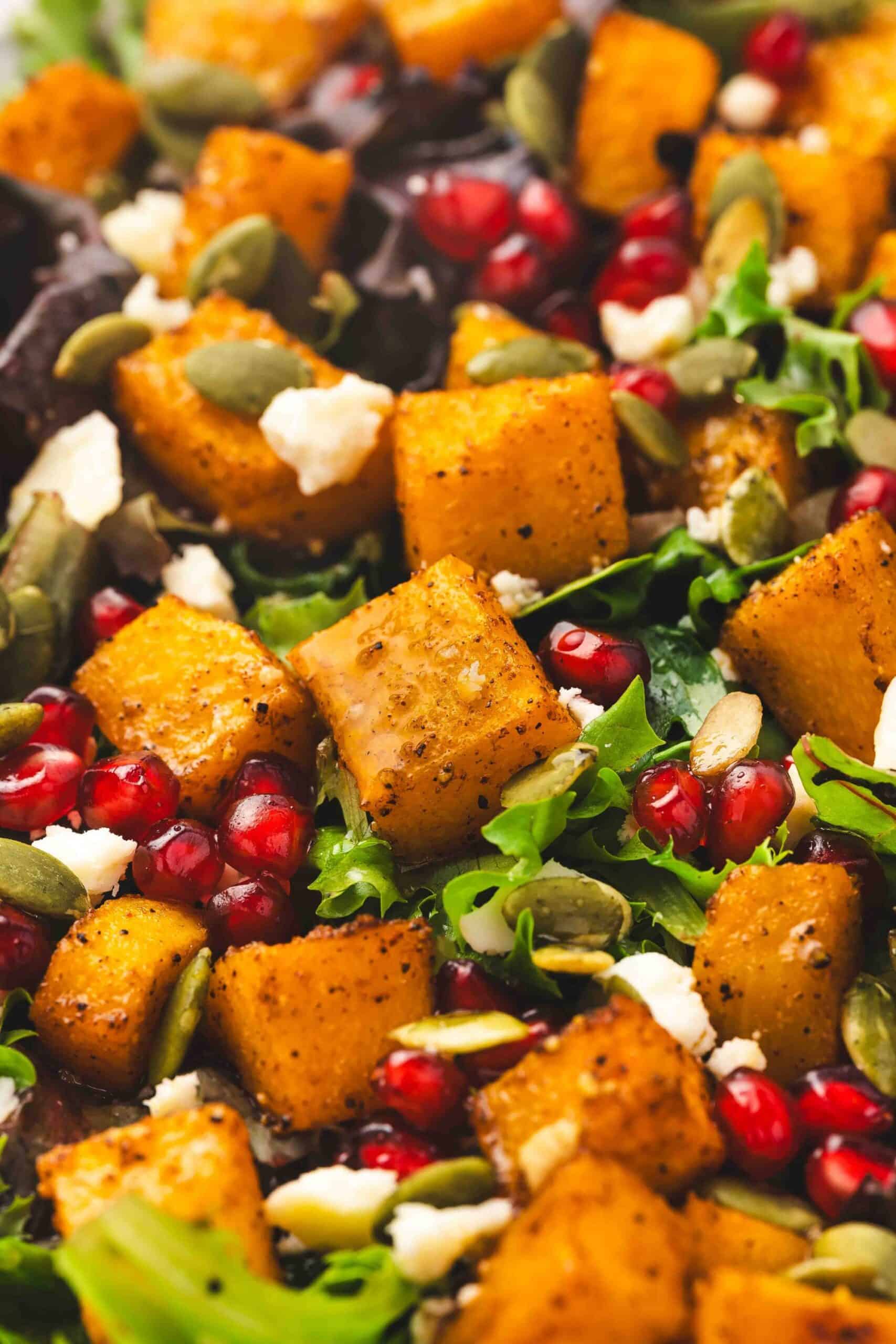 Golden cubes of roasted squash with creamy feta and crunchy pumpkin seeds on a platter