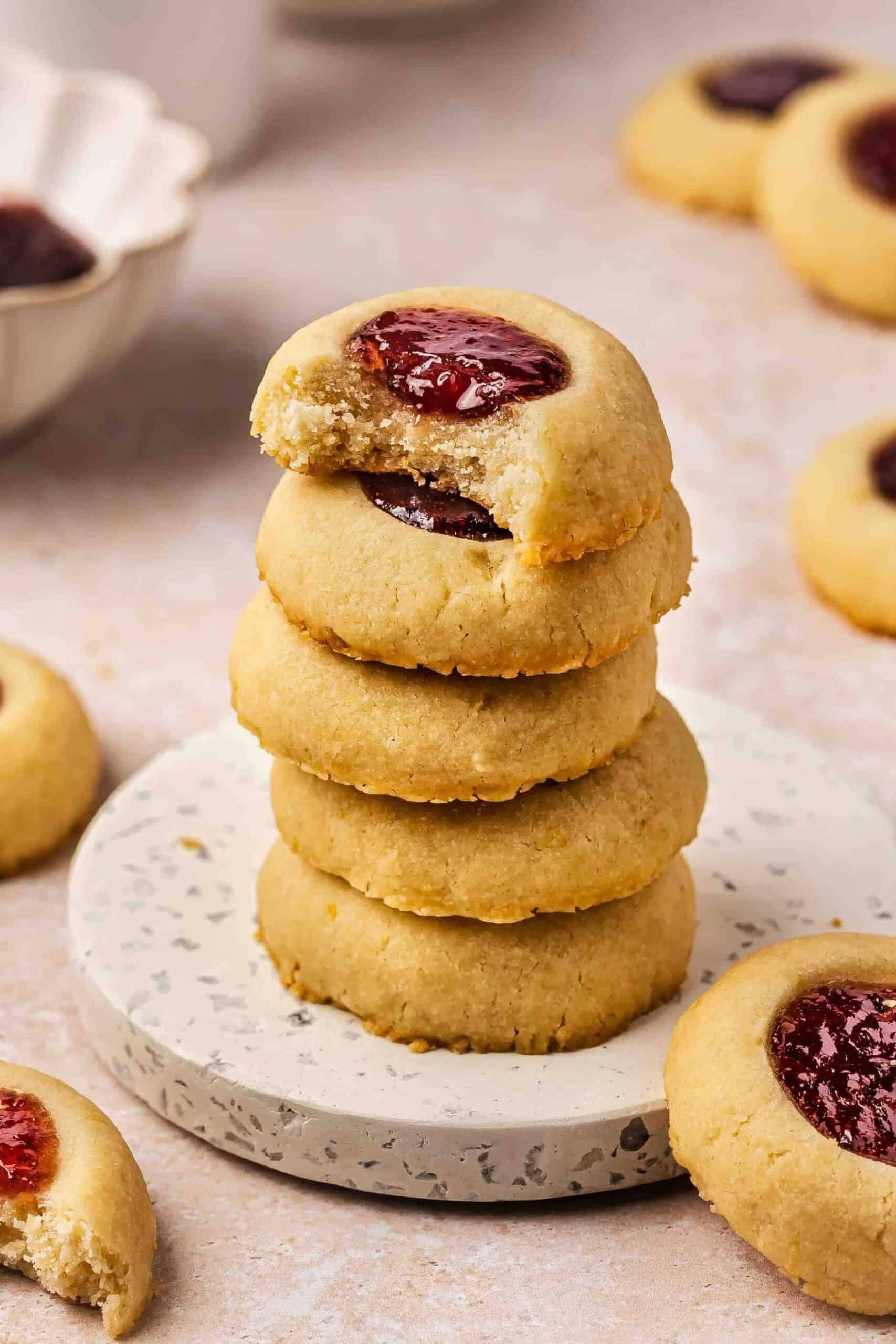 A bitten raspberry thumbprint cookie revealing its soft, buttery shortbread and sweet raspberry filling.