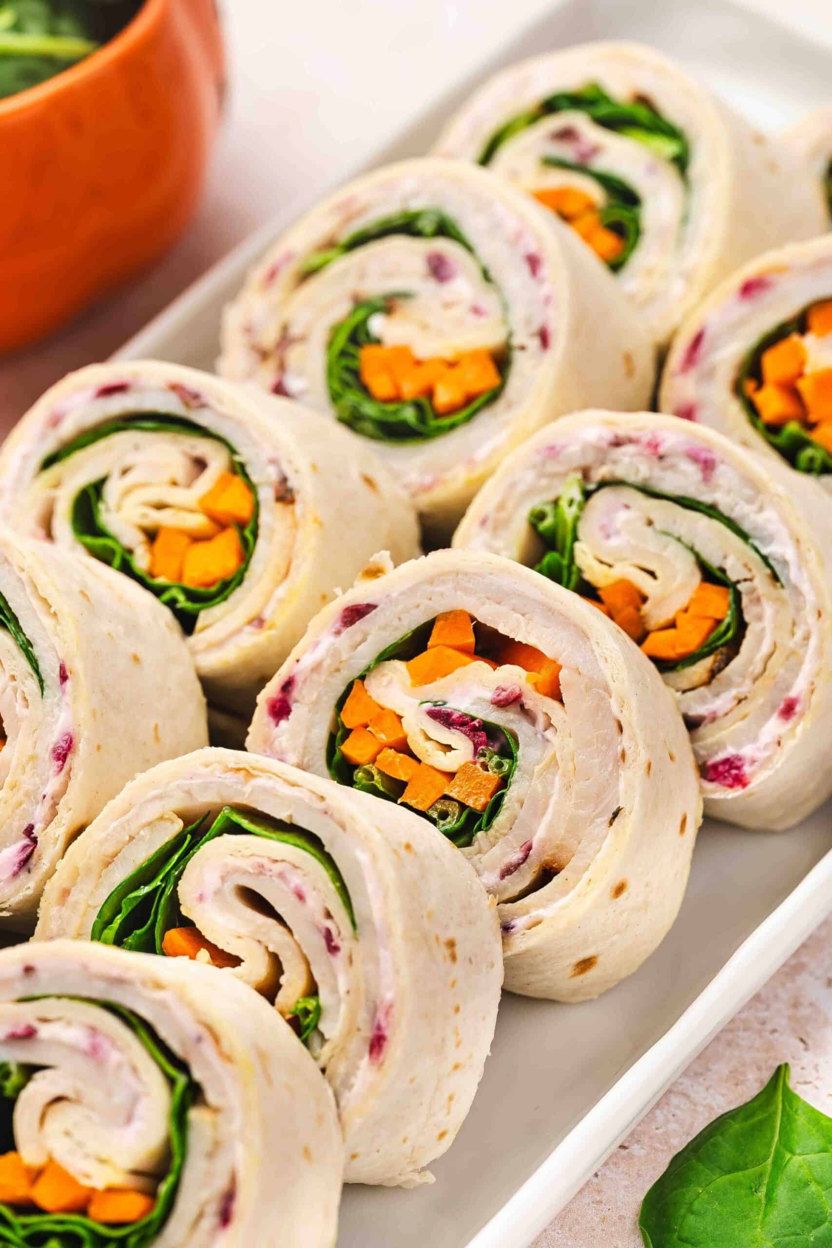 Sliced turkey roll-ups with creamy cranberry filling and colorful carrot strips.