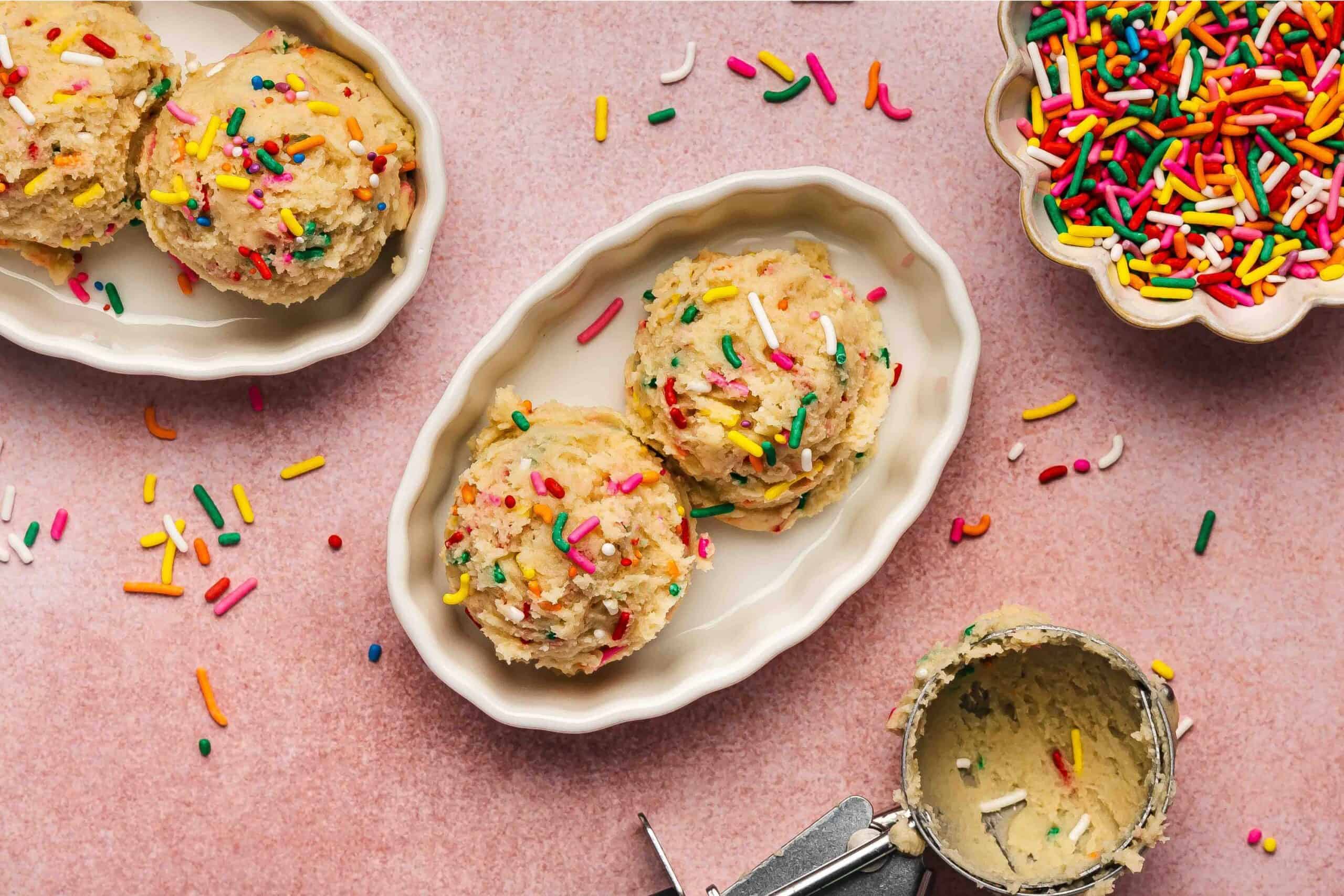 Funfetti-style edible sugar cookie dough in a ceramic bowl, colorful sprinkles showing.
