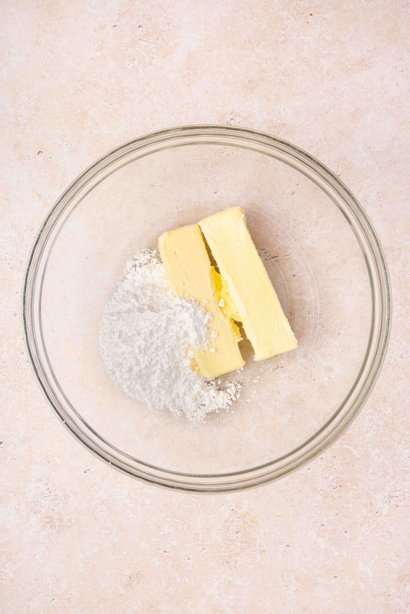 Softened butter and powdered sugar added to a mixing bowl for cookie dough.