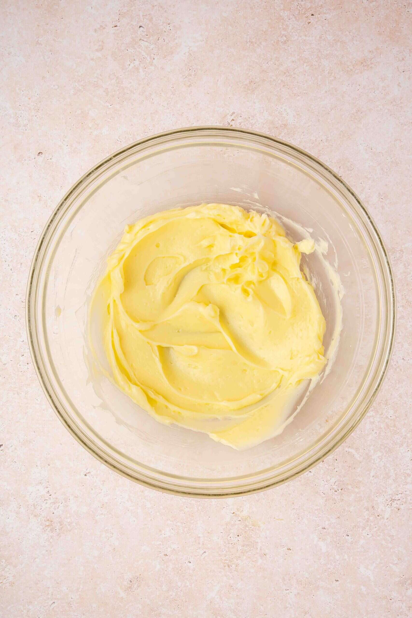 Hand mixer beating butter and sugar until light, smooth, and creamy in a bowl.