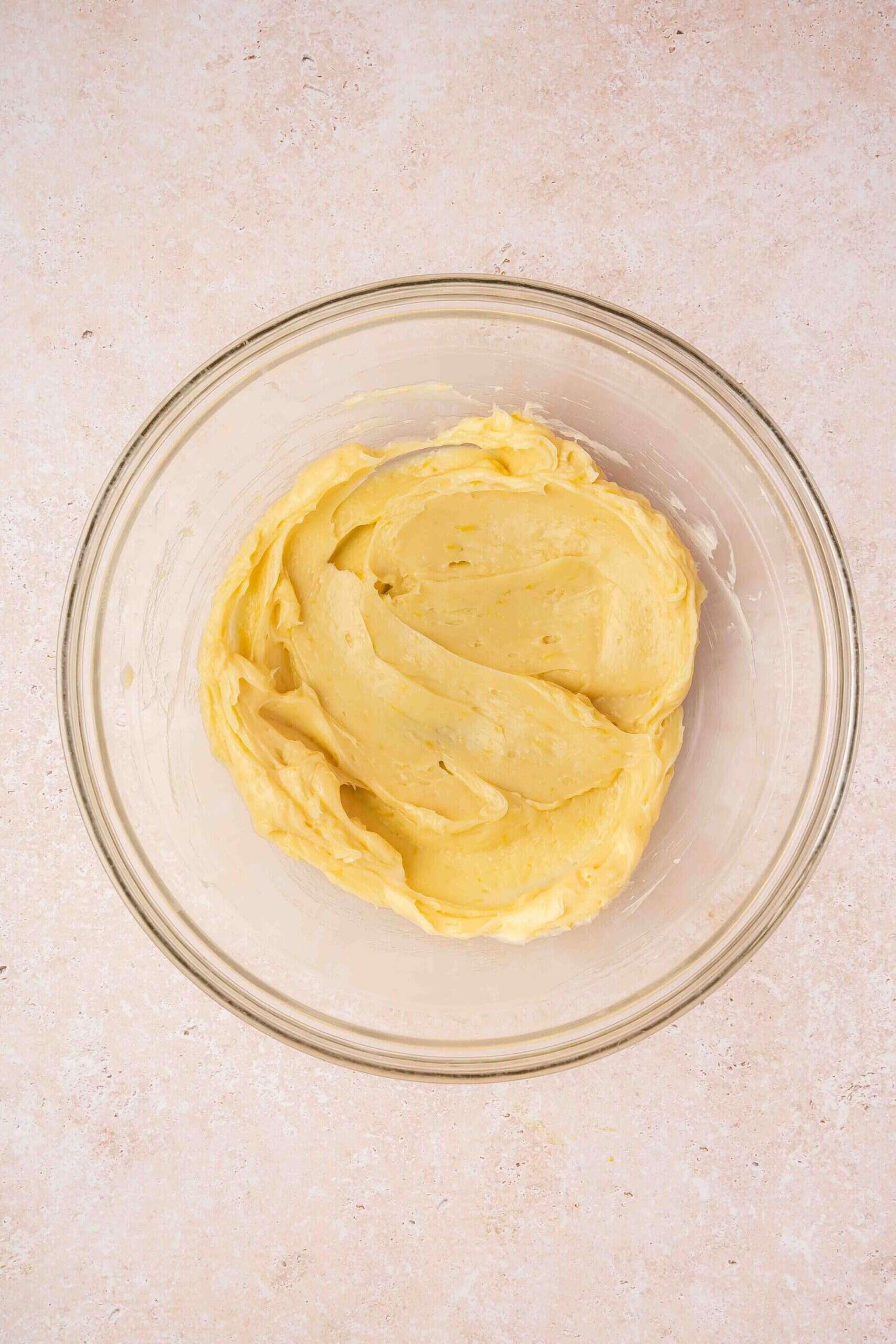 Hand mixer blending vanilla and lemon zest into the butter mixture until fragrant.