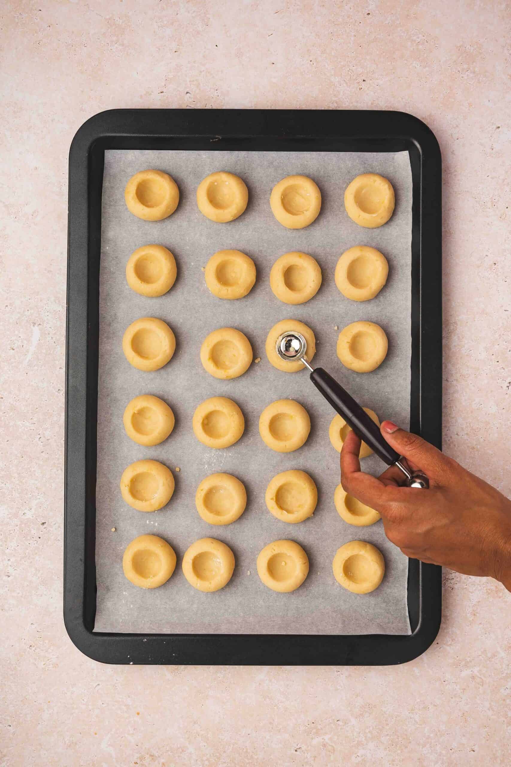 Making indentations in dough balls using a thumb before chilling in the fridge.