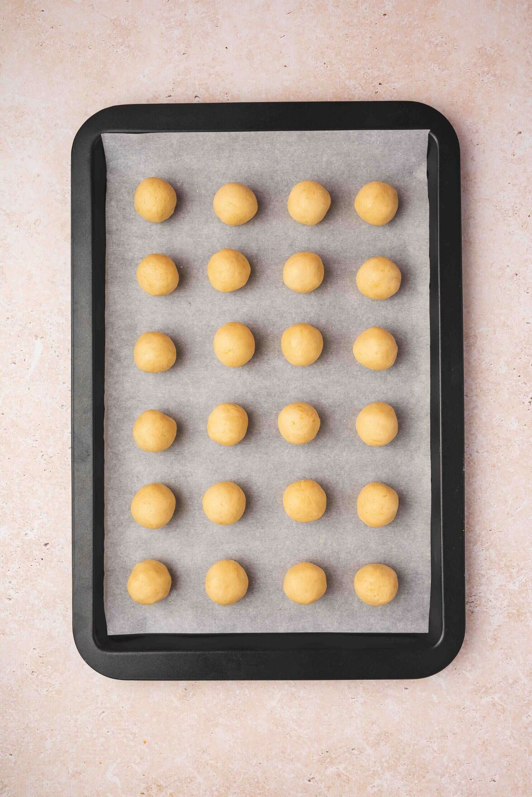 Rolling cookie dough into 1-inch balls and arranging them on a parchment-lined baking sheet.